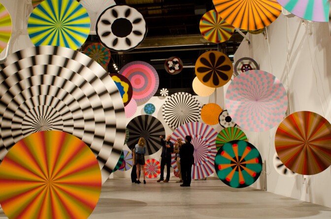 Discussing the art of Jim Drain & Ara Peterson, guests walk through the installation of spinning spirals.