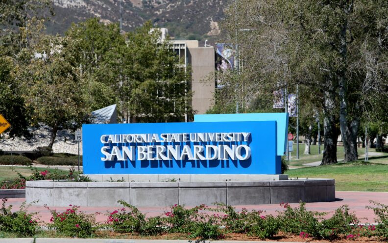 The California State University of San Bernardino sign with a library in the background.