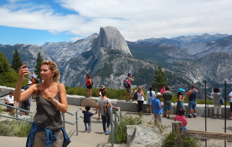 This August 5, 2015 photo shows a woman taking a selfie atop Glacier Point with a background view of Half Dome at Yosemite National Park.