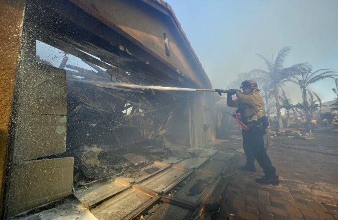 A fireman puts out a fire at a home in the Anaheim Hills neighborhood on October 9, 2017, after the Canyon Fire 2 spread quickly through the area.