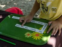 A preschool aged boy uses his recess time to play with a word puzzle.