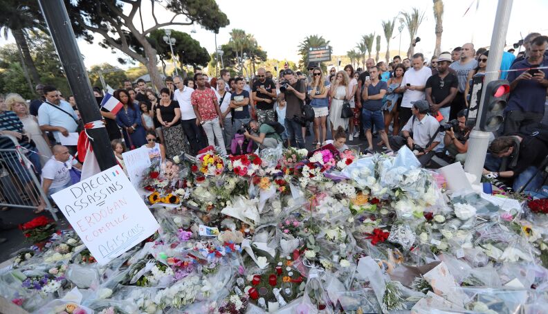People gather around a makeshift memorial to pay tribute to the victims of an attack in the French Riviera city of Nice on July 15, 2016, a day after when a man rammed a truck through a crowd celebrating Bastille Day, killing at least 84 people.
