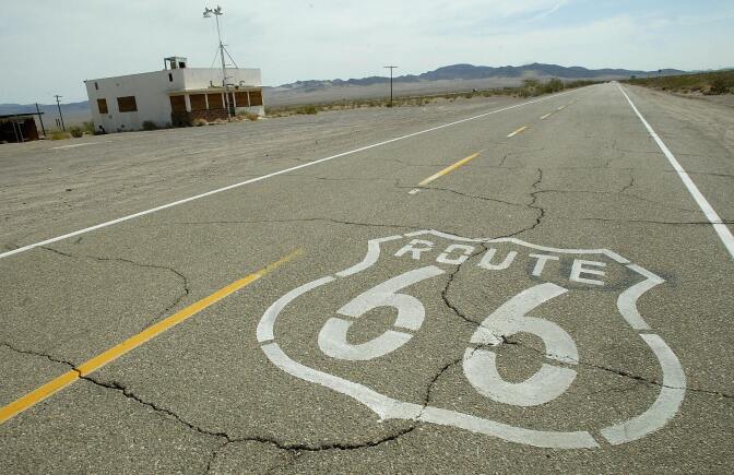 Route 66 is stenciled on the old road through an abandoned town in California's Mojave desert 14 July 2003. Route 66 is 2,448 miles (3,939kms) of roadway connecting Chicago to Los Angeles, now used by local traffic, road buffs and nostalgia-minded tourists. For midwestern farmers migrating to California to escape escaping the Dust Bowl in 1930's, the long stretch across the Mojave desert was considered one of the most grueling parts of the trip.  AFP PHOTO / Robyn BECK  (Photo credit should read ROBYN BECK/AFP/Getty Images)