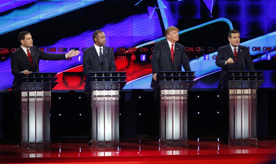 Marco Rubio, left, and Ted Cruz, right, both speak as Ben Carson, second from left, and Donald Trump, second from right, look on during the CNN Republican presidential debate at the Venetian Hotel & Casino on Tuesday, Dec. 15, 2015, in Las Vegas. (AP Photo/John Locher)