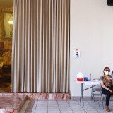 LOS ANGELES, CALIFORNIA - APRIL 09: Erendira Natalie receives her first dose of the Pfizer COVID-19 vaccine from a health care worker at a clinic targeting minority community members at St. Patrick's Catholic Church on April 9, 2021 in Los Angeles, California. St. John's Well Child and Family Center is administering COVID-19 vaccines in churches across South L.A. in a broad effort to bring vaccines to minority communities. (Photo by Mario Tama/Getty Images)