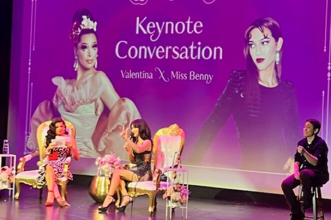Two drag queens in dresses and heels lead a panel discussion on stage at the LGBTQ Center in West Hollywood against a purple backdrop that reads "Queerceañera Keynote Conversation"