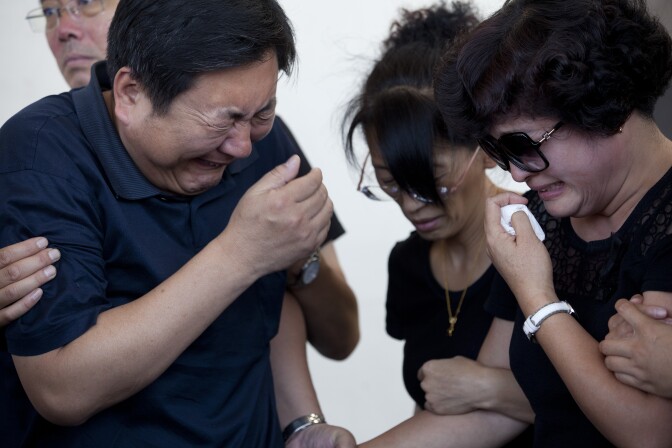 Songbo Ji, left, and his wife, Jinhui Du, far right, react after seeing their son, Xinran Ji, at the Universal Chung Wah funeral home in Alhambra, who was beaten by attackers near USC and later died in his apartment. His parents flew in from China with other family members to attend the funeral on Saturday.