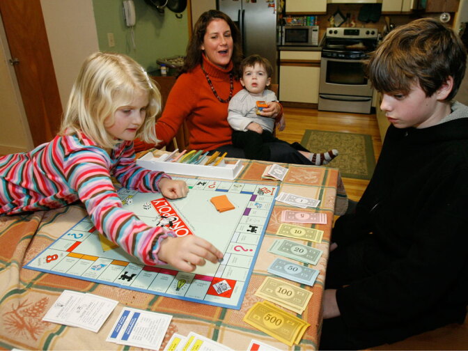 A family plays Monopoly in the kitchen of their home in Jericho, Vt.