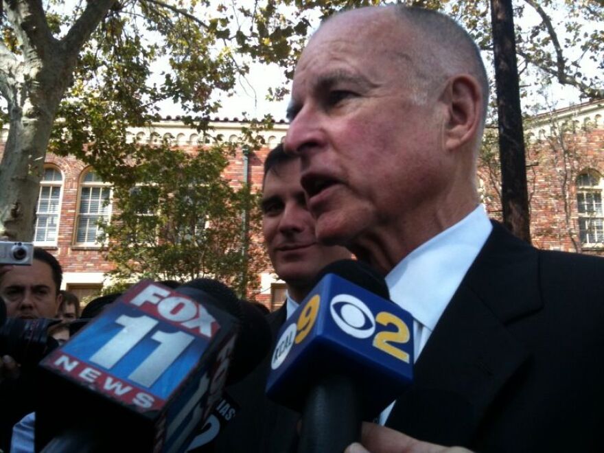 Democrat Jerry Brown talks to reporters outside Dorris Place Elementary School, where he claimed Republican Meg Whitman's plan to eliminate the capital gains tax would force deep cuts in education.