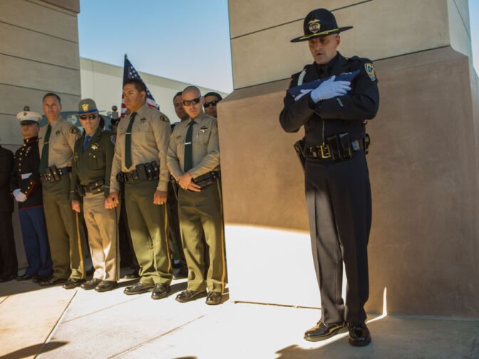 A Riverside Police Officer holds an American Flag that will be laid on-top of Michael Crain's coffin on February 13th, 2013.