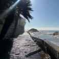 A flooded boardwalk along a coastline with eroded sand berms.