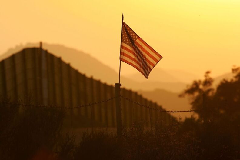 A U.S. flag put up by activists who oppose illegal immigration flies near the US-Mexico border fence in an area where they search for border crossers October 8, 2006 near Campo, California. The activists want the fence expanded into a fully-lit double-fenced barrier between the US (R) and Mexico. US Fish and Wildlife Service wardens and environmentalists warn that a proposed plan by US lawmakers to construct 700 miles of double fencing along the 2,000-mile US-Mexico border, in an attempt to wall-out illegal immigrants, would also harm rare wildlife. Wildlife experts say cactus-pollinating insects would fly around fence lights, birds that migrate by starlight in the desert wilderness would be confused, and large mammals such as jaguars, Mexican wolves, Sonoran pronghorn antelope, and desert bighorn sheep would be blocked from migrating across the international border, from California to Texas.