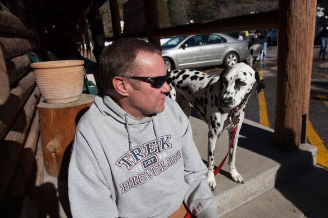 Rick Heltebrake relates the tale of how Christopher Dorner hijacked his truck on Highway 38 to reporters while his dog Suni hangs around.
