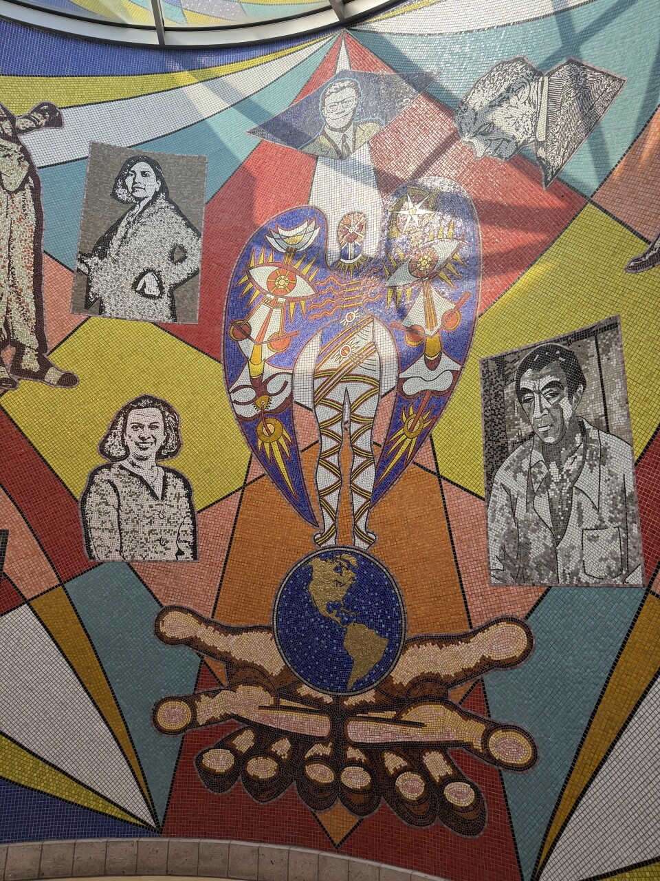 A vibrant and intricate mosaic mural composed of colorful geometric patterns and symbolic imagery.