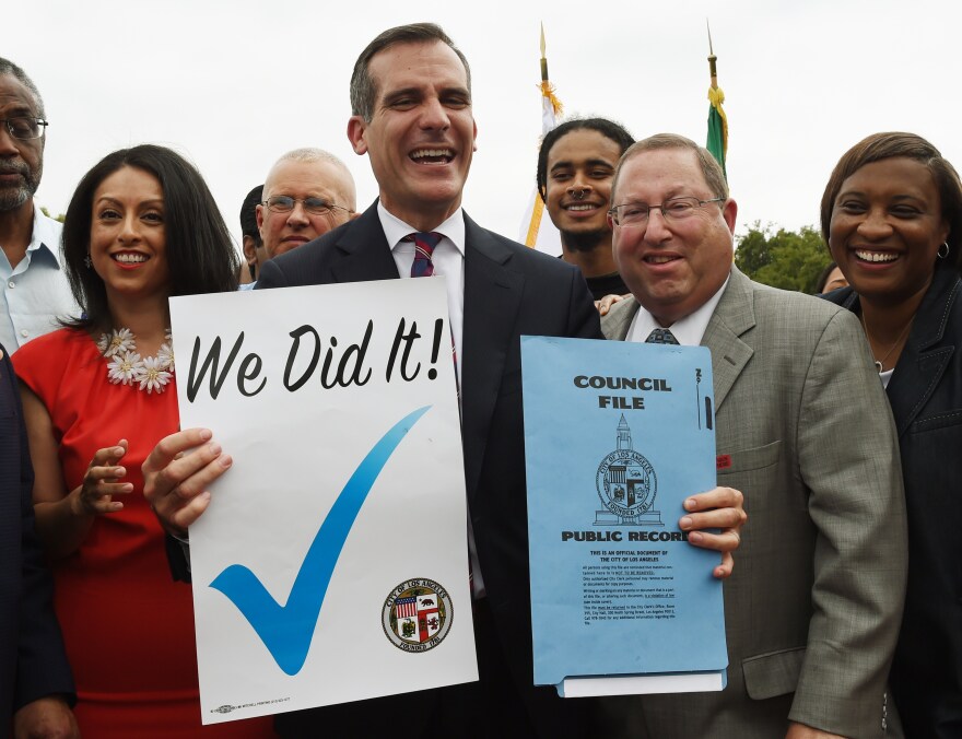 Los Angeles Mayor Eric Garcetti (C) celebrates with City Councilors and labor representatives after he signed into law an ordinance raising the minimum wage to USD 15 an hour by 2020, in Los Angeles, California on June 13, 2015.  Los Angeles is the first major city to sign the ordinance and the increase will be USD 6 from the current  USD 9 per hour.        AFP PHOTO / MARK RALSTON        (Photo credit should read MARK RALSTON/AFP/Getty Images)