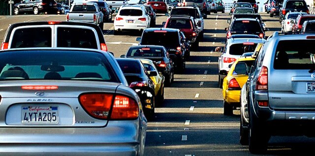 Cars on a freeway are shown from behind, stopped in traffic.