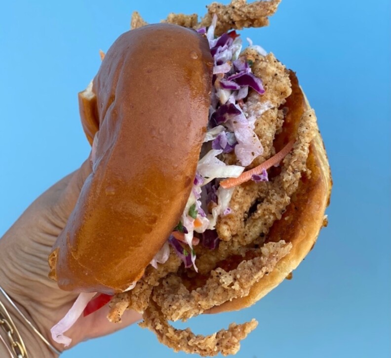 A hand holds a soft-shell crab sandwich.
