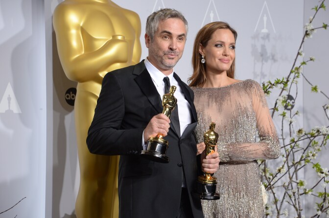 Director Alfonso Cuarón (L), winner of Best Achievement in Directing for 'Gravity', and actress Angelina Jolie pose in the press room during the 86th Academy Awards on March 2nd, 2014 in Hollywood, California.
