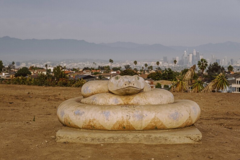 Behind this giant snake sculpture is a spectacular vista of downtown L.A.