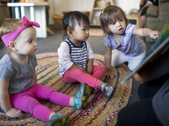 Eighteen-month-old Louisa Beck, left, and 22-month-olds Maya Luu Guayasamin and Amelie Schuster listen as Maria Palazzolo reads a book in Spanish on Thursday morning, Nov. 12 2015 at The Family Nest.