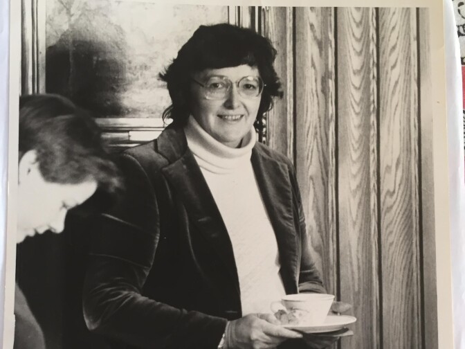 Rosemary Radford Ruether wears a blazer and white turtleneck while she holds a teacup in a black and white image.