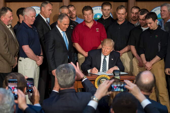 Surrounded by miners from Rosebud Mining, President Donald Trump signs the Energy Independence Executive Order at the Environmental Protection Agency headquarters in Washington, DC, on March 28, 2017. Trump claimed an end to the "war on coal" as he moved to roll back climate protections enacted by President Obama.