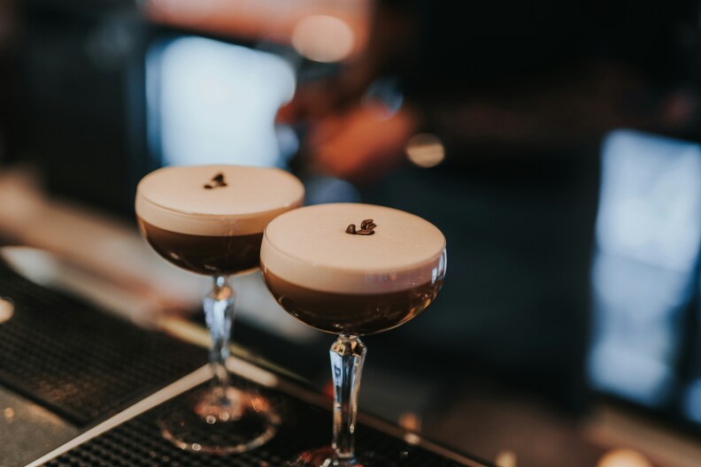 Two glasses of espresso martini sitting on a bar.