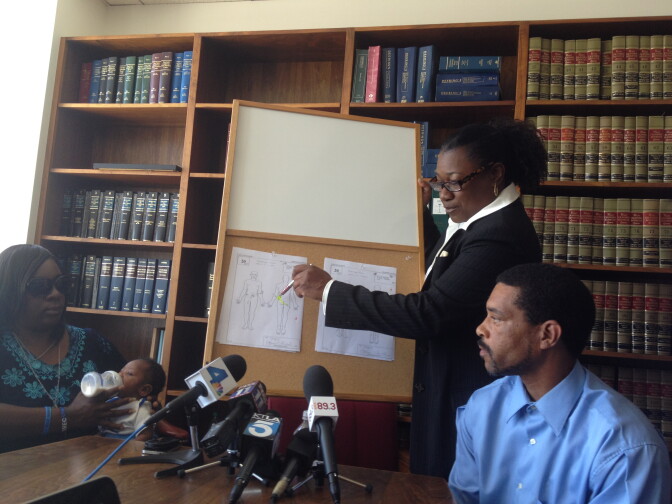 Attorney Caree Harper points to diagrams in the autopsy report of Kendrec McDade, 19, who was shot and killed by Pasadena police. His parents sit to the left and right of Harper. 