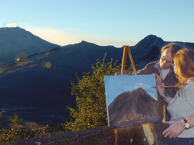 Teri Dewey, right, assisted by her husband, Joe Dewey, adds a steam plume to her painting of Mount St. Helens, after setting up her easel at Elk Creek Overlook in Washington on October 14, 2004.