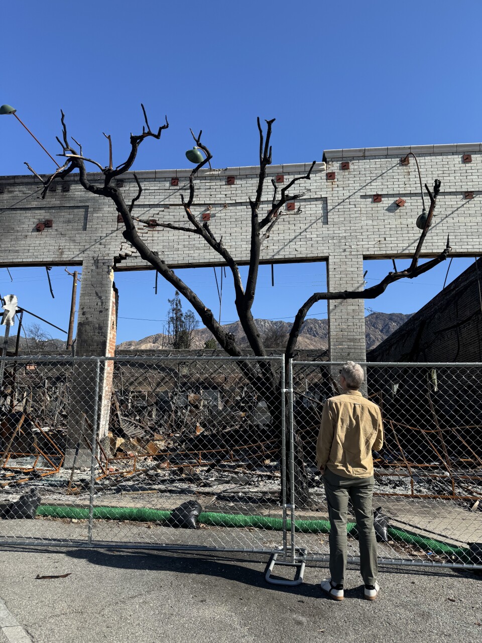 Man stands in front of destroyed structure.
