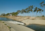 Water rushes through a concrete channel into a wide spreading basin.