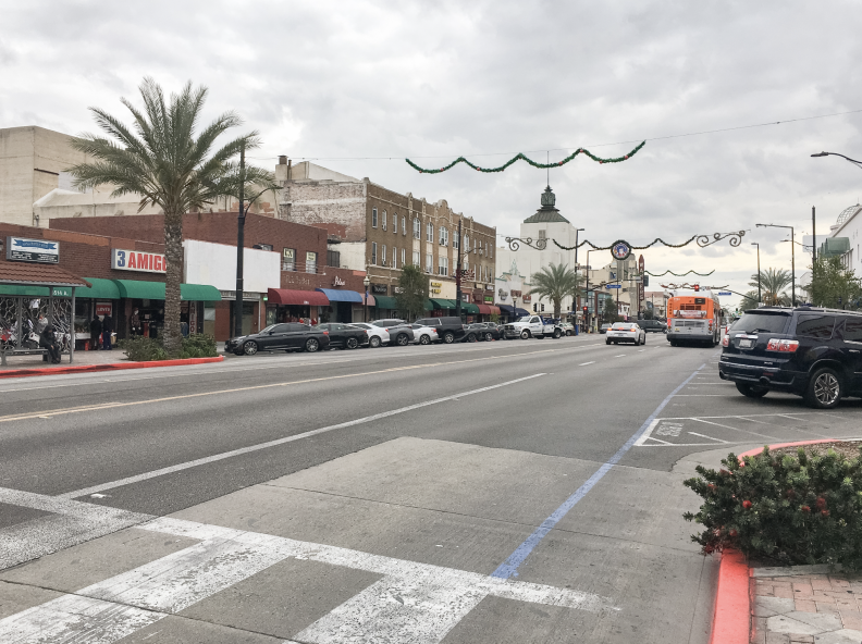 Parked cars and holiday decorations across a wide boulevard.