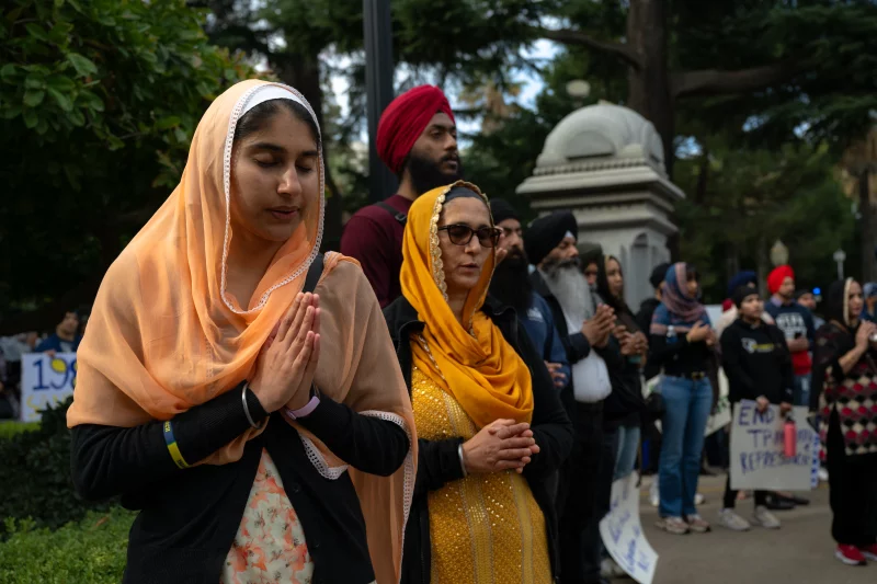 People in headscarves and turbans stand outside