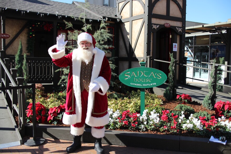 Santa stands outside of his house at the Citadel Outlets in Commerce for a Santa Cares event.