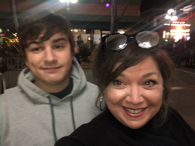 Nick and Deborah Smith look into the camera for a photo. Deborah wears a black top and is smiling, glasses perched atop her head. Nick wears a grey hoodie and is also smiling. 