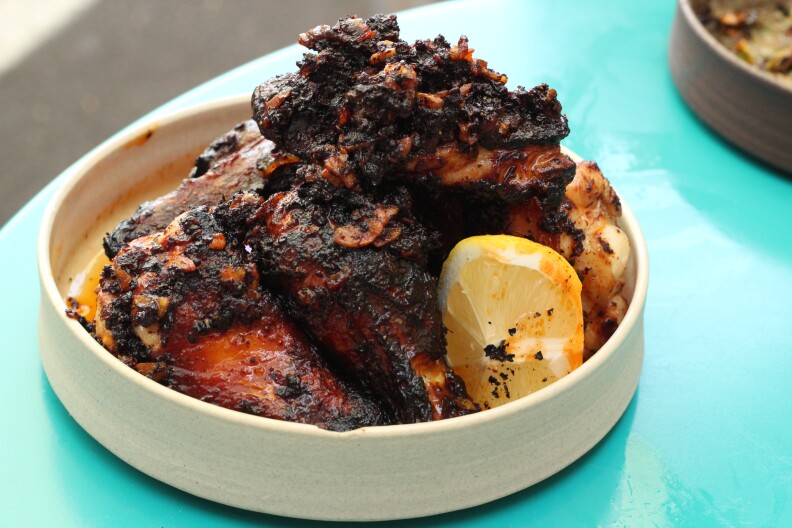 a bowl of charred chicken wings sits on a turquoise table