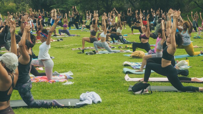 Several brown-skinned people engage in a yoga pose at a park. 