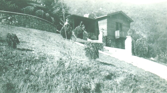 A brick and wood structure is seen in black and white. The Verdugo Lodge is at the top of a hill. 