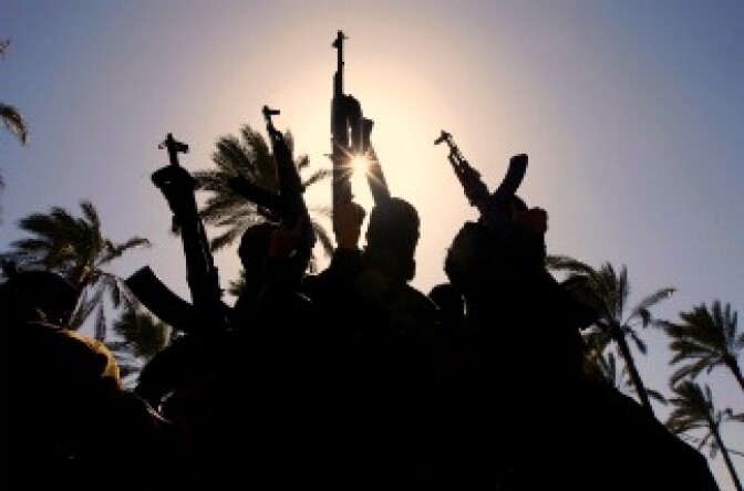 Masked Palestinian Islamic Jihad militants hold up their weapons as they wait next to the family house of Abdelmajid Shahin, one of their members killed the previous day by Israeli military fire, during his funeral in the Deir al Balah refugee camp in the southern Gaza Strip, on February 28, 2011.