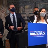 OAKLAND, CALIFORNIA - MAY 10: California Gov. Gavin Newsom (C) buttons his jacket as he prepares to take photo with state and local leaders during a press conference at The Unity Council on May 10, 2021 in Oakland, California. California Gov. Gavin Newsom announced a $100 billion economic recovery package for the state that would include a new round of $600 stimulus checks for low-income residents making up to $75,000 a year. An estimated two out of three Californians would receive the check and families with children would receive an additional $500. Newsom also announced a projected $75.7 billion budget surplus compared to last year's projected $54.3 billion shortfall. (Photo by Justin Sullivan/Getty Images)
