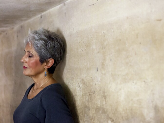 In this March 31, 2013 photo released by Metropole Hanoi, Joan Baez stands with her back to the wall of an historic bomb shelter under the Metropole Hotel in Hanoi, Vietnam. The folk singer and social activist spent a few days recently reliving her past, returning to Hanoi for the first time since December 1972, when American B-52s were raining bombs on it.  
