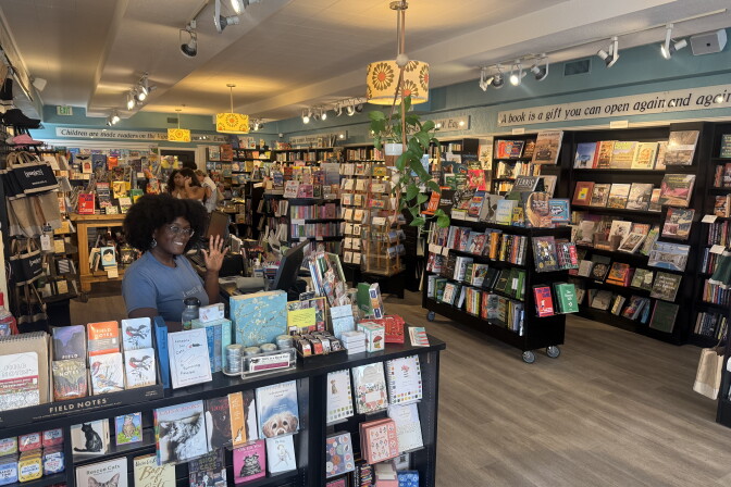 A woman in a blue shirt stands in pages: a bookstore. She is surrounded by books on all sides.