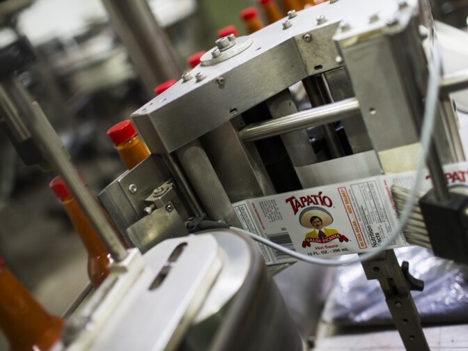 Labels are put on containers of hot sauce at Tapatio Foods in Vernon on Thursday morning, Jan. 14, 2016.