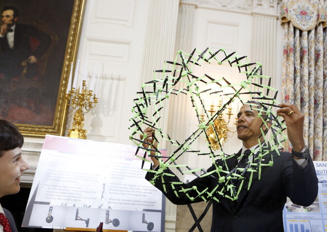 U.S. President Barack Obama looks at the project of Peyton Roberston (L) from Florida, winner of the Discovery 3M Young Scientist, for his "Sandless sand bags" project during the 2014 White House Science Fair at the White House, May 27, 2014 in Washington, DC.