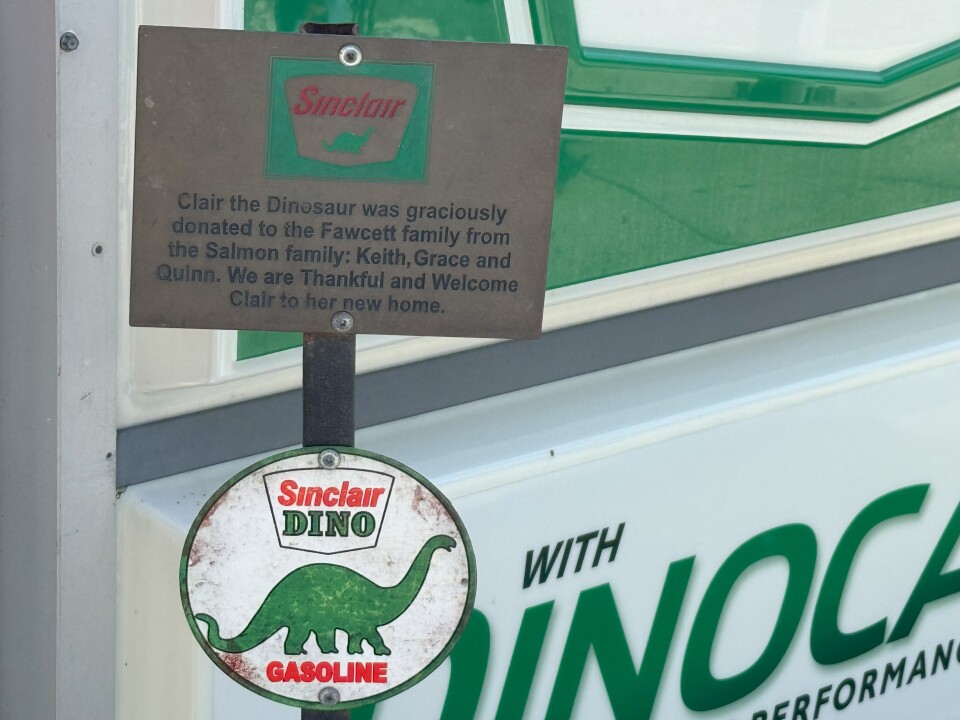 A sign reads "Clair the Dinosaur was graciously donated to the Fawcett family from the Salmon family: Keith, Grace and Quinn. We are Thankful and Welcome Clair to her new home. 