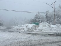 A sign pointing to Big Bear Lake and Lake Arrowhead is nearly covered in snow