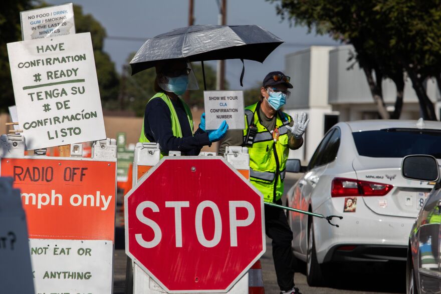A Testing Center specialists with personal protective equipment (PPE) assist drivers at a drive-in Covid-19 testing site in south Los Angeles, California on November 14, 2020. - After California passed 1 million coronavirus cases a travel advisory was issued on November 13 urging a two-week quarantine for those arriving from other states or countries. (Photo by Apu GOMES / AFP) (Photo by APU GOMES/AFP via Getty Images)