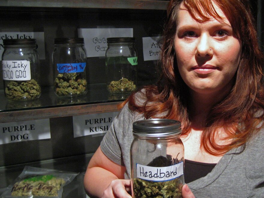 SaraJane Sinclair, owner of the SaraJane&Co. shop in Sacramento, Calif., holds a jar of medical marijuana. Sinclair says she called more than 50 insurance companies before she found coverage through Statewide Insurance Services.
