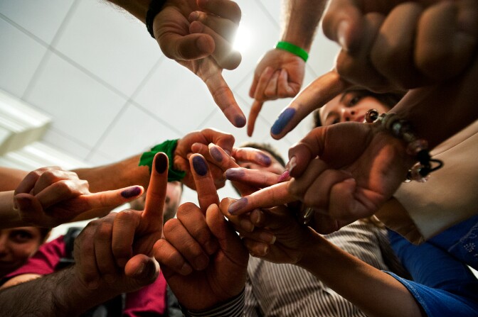 Voters hold up their right index fingers after participating in the Iranian presidential election on Friday at the Westin Hotel near Los Angeles International Airport.