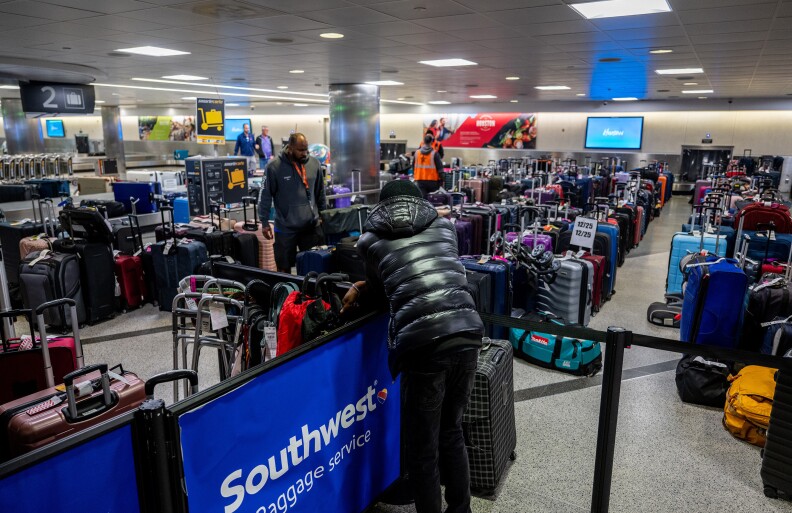 A person in a puffy kacket leans on a Southwest baggage service sign